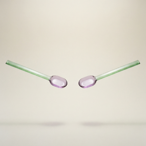 Two glass straws with pink oval tips on a beige background