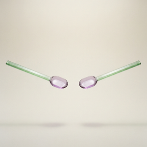 Two glass straws with pink oval tips on a beige background