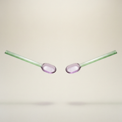 Two glass straws with pink oval tips on a beige background