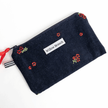 Navy corduroy zipper pouch with hand-embroidered red flowers, red ribbon pull and striped tab, handmade from upcycled vintage fabric by a Montreal artisan — Pochette zippée en velours côtelé marine avec fleurs rouges brodées à la main, tirant rouge et languette rayée, fabriquée à partir de tissus vintage recyclés par une artisane montréalaise.