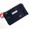 Navy corduroy zipper pouch with hand-embroidered red flowers, red ribbon pull and striped tab, handmade from upcycled vintage fabric by a Montreal artisan — Pochette zippée en velours côtelé marine avec fleurs rouges brodées à la main, tirant rouge et languette rayée, fabriquée à partir de tissus vintage recyclés par une artisane montréalaise.