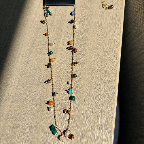 Gold-plated semi-precious stone charm necklace displayed on wood block, colorful stones including amethyst and turquoise — Reyca / Collier charm plaqué or avec pierres semi-précieuses exposé sur bloc de bois, pierres colorées dont améthyste et turquoise — Reyca