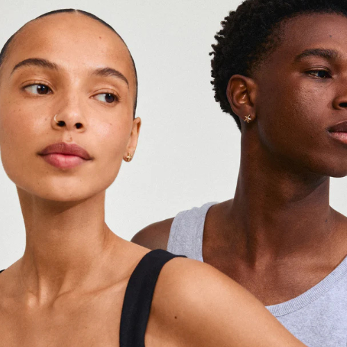 Mini gold starfish stud earrings worn by two models, man and woman, against light background — Reyca / Petites boucles d'oreilles clou étoile de mer dorées portées par deux mannequins, homme et femme, sur fond clair — Reyca