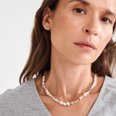 Woman wearing gold plated beaded necklace with sand-toned beads and starfish charms styled as a choker | Femme portant un collier perlé plaqué or avec perles sablées et breloques étoile de mer en style choker