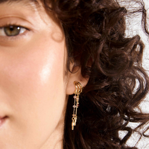 Gold triple hoop drop earrings with glass bead charms worn on model with dark curly hair — Reyca / Boucles d'oreilles triple anneau doré avec charms en perles de verre portées par un mannequin aux cheveux bouclés foncés — Reyca