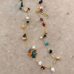 Full-length gold semi-precious stone charm necklace on white surface, adjustable chain and colorful stone charms — Reyca / Collier charm pierres semi-précieuses plaqué or en longueur complète sur surface blanche, chaîne ajustable et pierres colorées — Reyca