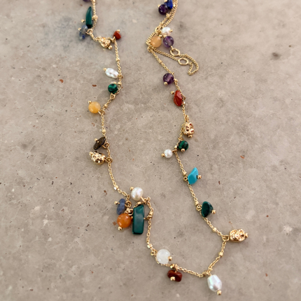 Full-length gold semi-precious stone charm necklace on white surface, adjustable chain and colorful stone charms — Reyca / Collier charm pierres semi-précieuses plaqué or en longueur complète sur surface blanche, chaîne ajustable et pierres colorées — Reyca