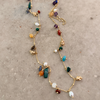 Full-length gold semi-precious stone charm necklace on white surface, adjustable chain and colorful stone charms — Reyca / Collier charm pierres semi-précieuses plaqué or en longueur complète sur surface blanche, chaîne ajustable et pierres colorées — Reyca