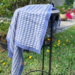 Hand block-printed slate blue cotton scarf with white crescent pattern, Foulard en coton bleu ardoise imprimé à la main avec un motif croissant blanc, porté autour du cou.