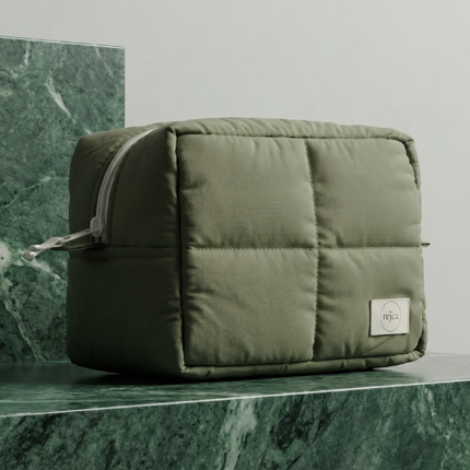 Green quilted pouch on a green marble surface with a neutral background
